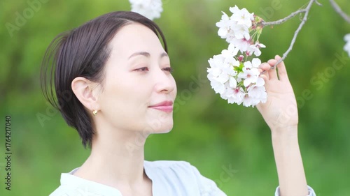 桜の花びらを見る若い女性　ライフスタイルイメージ