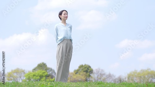 緑の丘の上を歩く若い女性　ライフスタイルイメージ