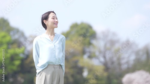 緑の丘の上を歩く若い女性　ライフスタイルイメージ