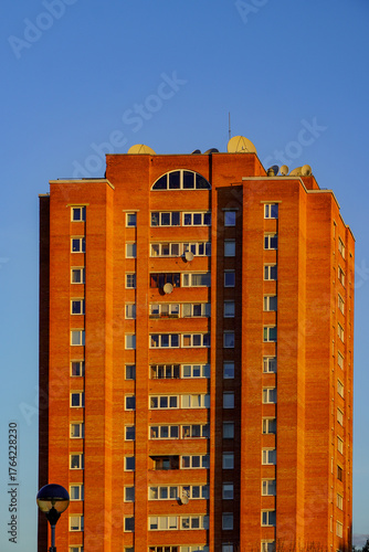 Sunset view of a modern brick apartment building against a clear blue sky in an urban setting