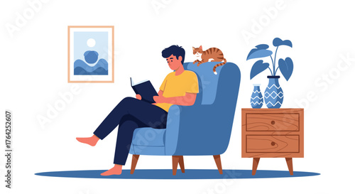 Young man reading a book while sitting in a comfortable armchair with a cat.