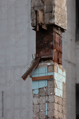A Close-Up Of A Ruined Industrial Column With Broken Tiles, Rusted Rebar, And Crumbling Concrete.