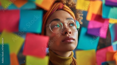 Gen z worker with glasses wearing a bright yellow scarf while brainstorming with sticky notes