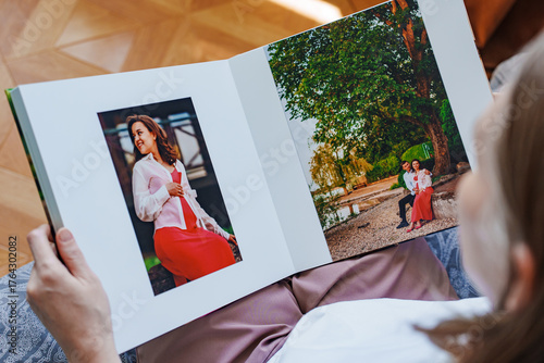 woman is holding and flipping through a photo book with a pregnancy photo shoot