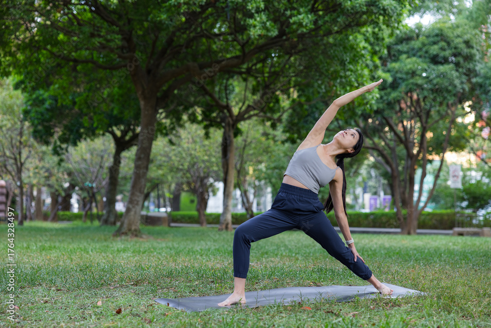 Fototapeta premium Woman practicing reverse warrior two yoga pose outdoors