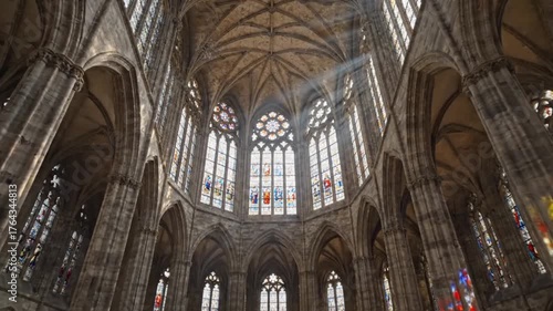 Sunlight streaming through stained glass windows in a grand gothic cathedral interior.