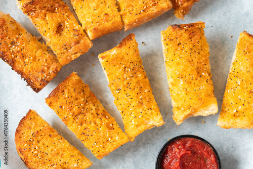 Garlic bread seasoned with sesame seeds and served with a side of marinara sauce.