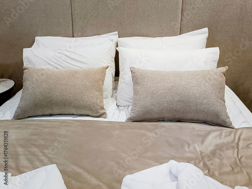 White and gray pillows on a bed with headboard. Hotel room interior.