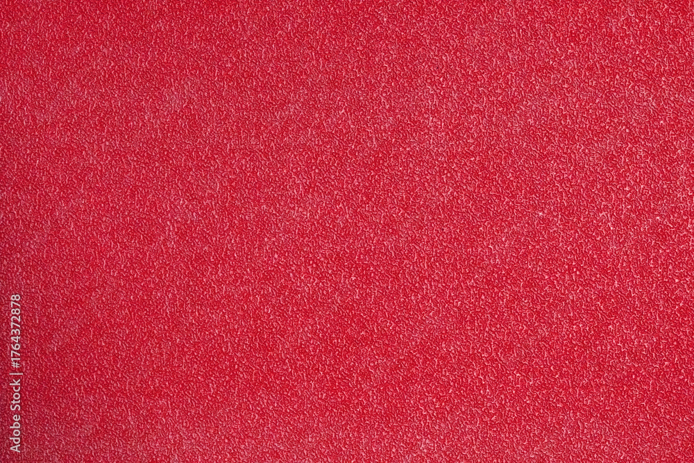 Fototapeta premium A vibrant, high-texture close-up of a synthetic sports court surface in an intense, bright red color, ideal for use as a dynamic abstract background or backdrop.
