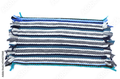 Handwoven fabric mat made from colorful recycled textile strips in shades of blue, gray, and white. Eco-friendly handmade craft showcasing traditional weaving technique and sustainable home decor