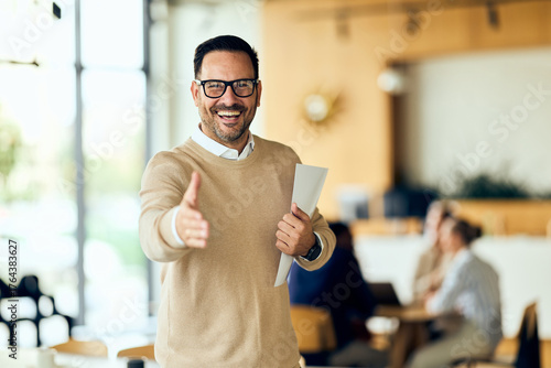 Affable Man in Beige Sweater Welcomes Colleagues with Handshake in Modern Office Setting