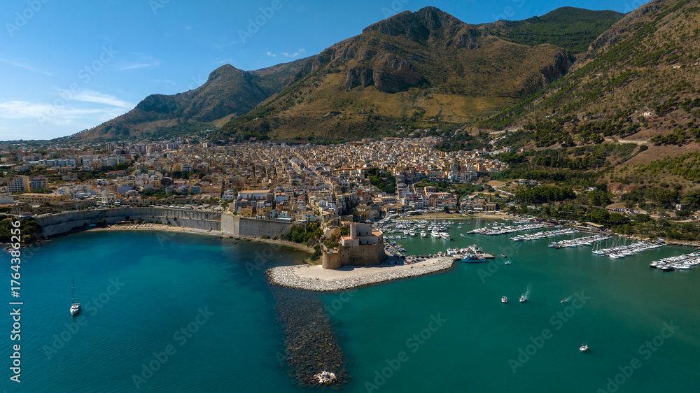 Obraz premium Aerial view of Castellammare del Golfo, a small town located in the province of Trapani, Sicily, Italy. The town overlooks the Mediterranean Sea and has mountains behind it.