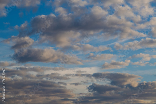 A band of dark gray clouds in the blue sky with reflections of the evening sun and clouds receding into the sunset haze.