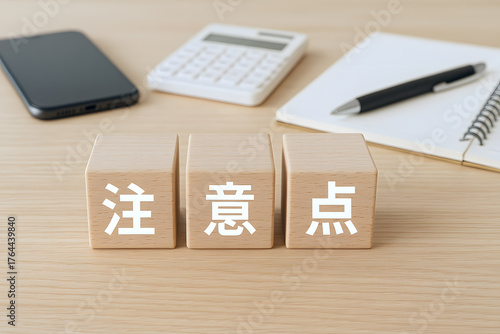 木目のテーブルに置かれた電卓やメモ帳と注意点と書かれた木製ブロックが並ぶ重要事項
