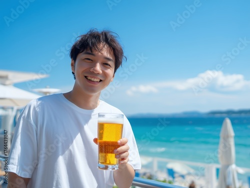 青い海と空が広がるリゾートビーチのテラスで冷えたビールジョッキを持ち笑顔の日本人男性