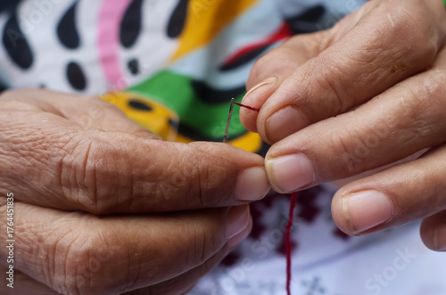 A skilled artisan carefully inserting threading into a needle to complete a beautiful floral design. Every stitch shows precision, dedication, and the art of creating something truly unique