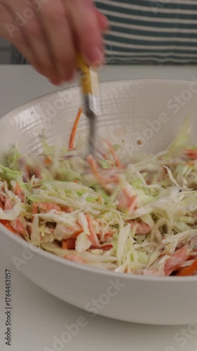 mixing dressing in cabbage salad in bowl coleslaw