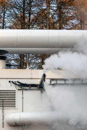 Industrial steam vents release white vapor outdoors