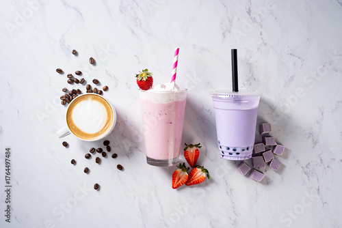 Coffee, strawberry milkshake, and taro bubble tea on marble table, isolated on white background