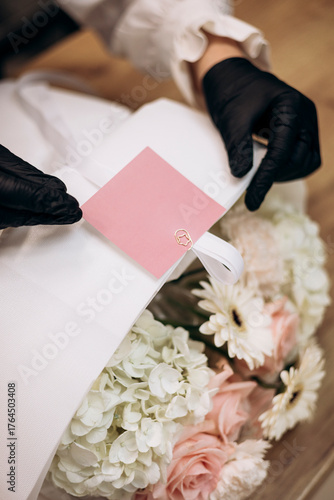 Fényképezés Florist attaching pink card to bouquet with roses, hydrangeas, and gerberas