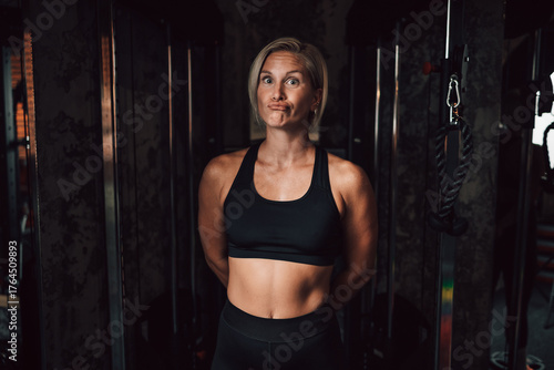 Caucasian fitness woman make funny faces while posing in a gym environment