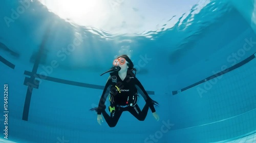 Diver Swimming Underwater in a Blue Pool with Sunlight.