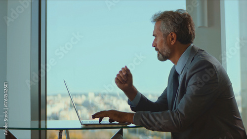 Obraz na plátně Experienced senior corporate leader diligently typing on a laptop, reflecting ex