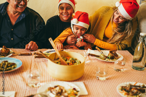Happy latin family having fun eating together during Christmas time - Holiday concept - Soft focus on kid face