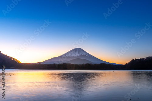Beautiful sunrise view of Mount Fuji reflected on calm lake water, with clear blue sky and warm morning light. Perfect for travel, nature, landscape, and Japan tourism themes on stock platforms.