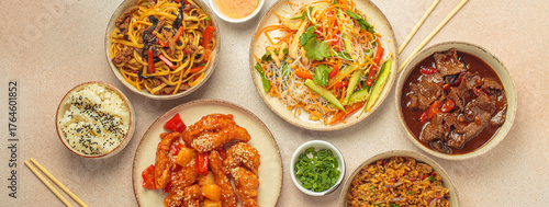 Assorted Chinese dishes, sweet and sour chicken, beef in sauce, noodles, fried rice, salad and wooden chopsticks. Chinese or Asian restaurant concept