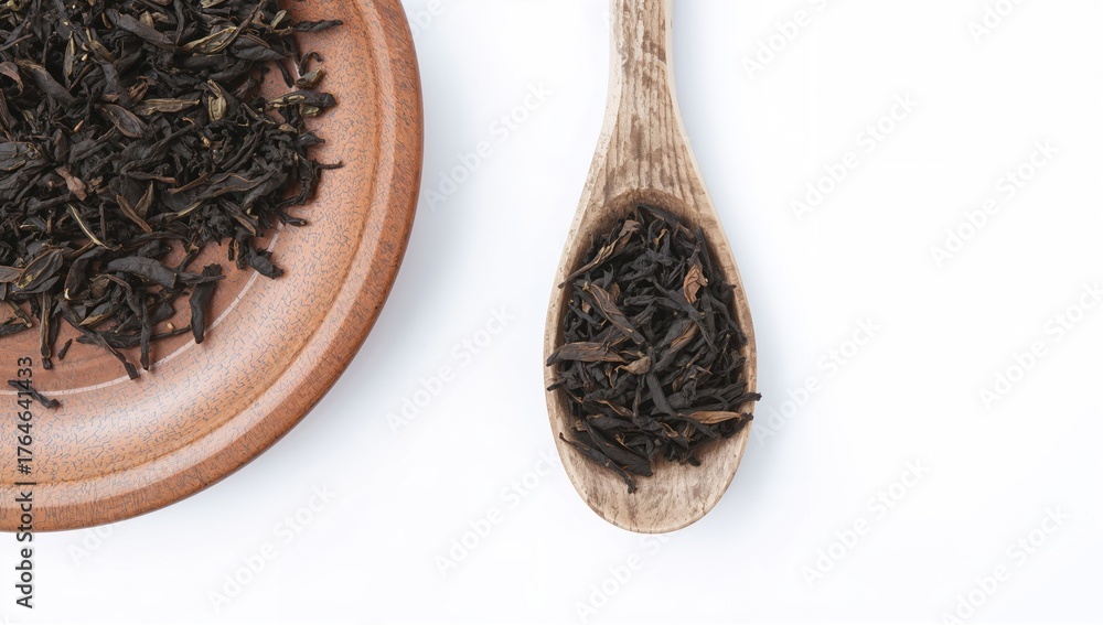 Fototapeta premium Black dried tea leaves displayed on a wooden spoon and round tray