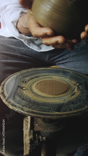 A skilled potter completes a clay jug on a spinning wheel in a workshop, showcasing his talent and craftsmanship.