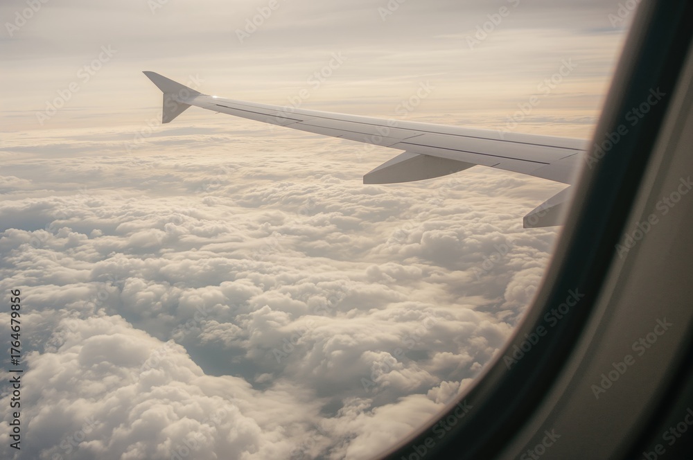 Fototapeta premium View of Aircraft Wing and Clouds from Window Seat. Aerial Perspective.