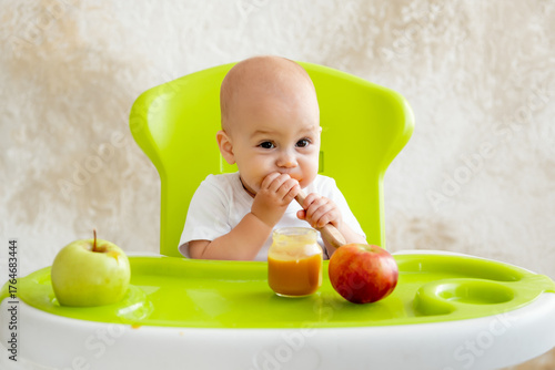 baby eating an apple, small child eating in a high chair, eating fruits at home, healthy eating, first solid food, baby food concept