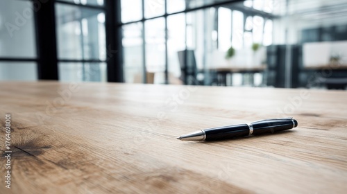 A single pen lying on a wooden desk with blurred background, professional workspace vibe.