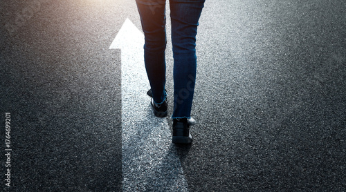 Woman standing on asphalt road with the arrow sign