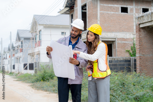  Construction workers with safety gear holding blueprints and discussing project design at residential building area teamwork, architecture, engineering, and housing development concept.
