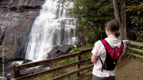 A young woman stands near Rainbow Falls in the Blue Ridge Mountains of North Carolina.