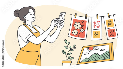 A smiling woman in an apron photographs her handmade artwork and plant with a smartphone.