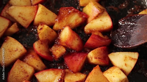 Close-up of caramelized apples cooking with cinnamon and sugar in a frying pan.