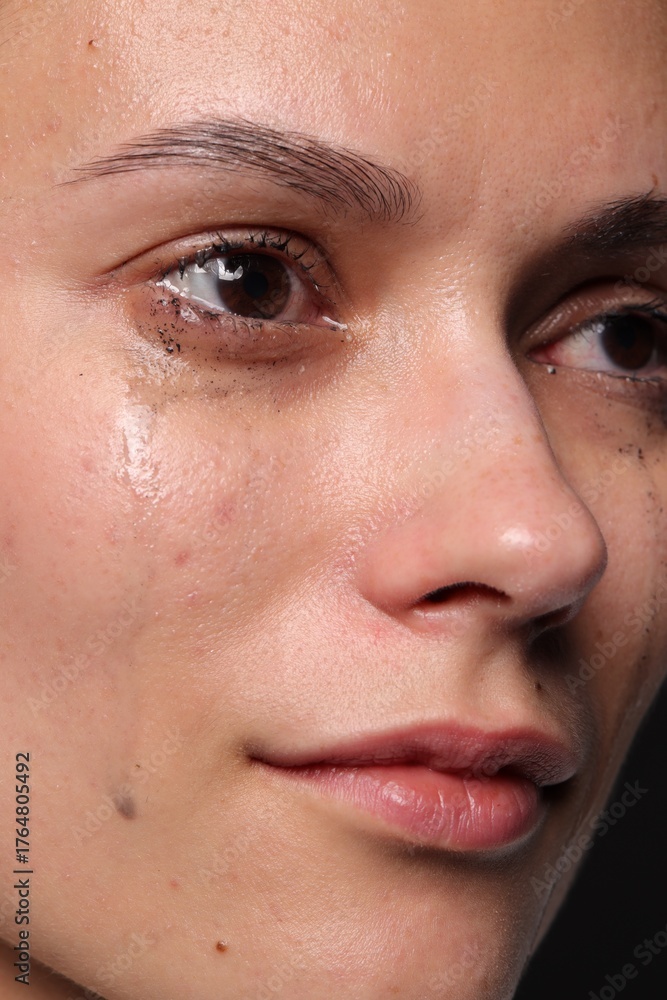 Naklejka premium Sad woman crying on black background, closeup
