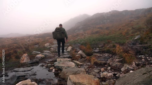 A man hiking up a foggy mountain trail
