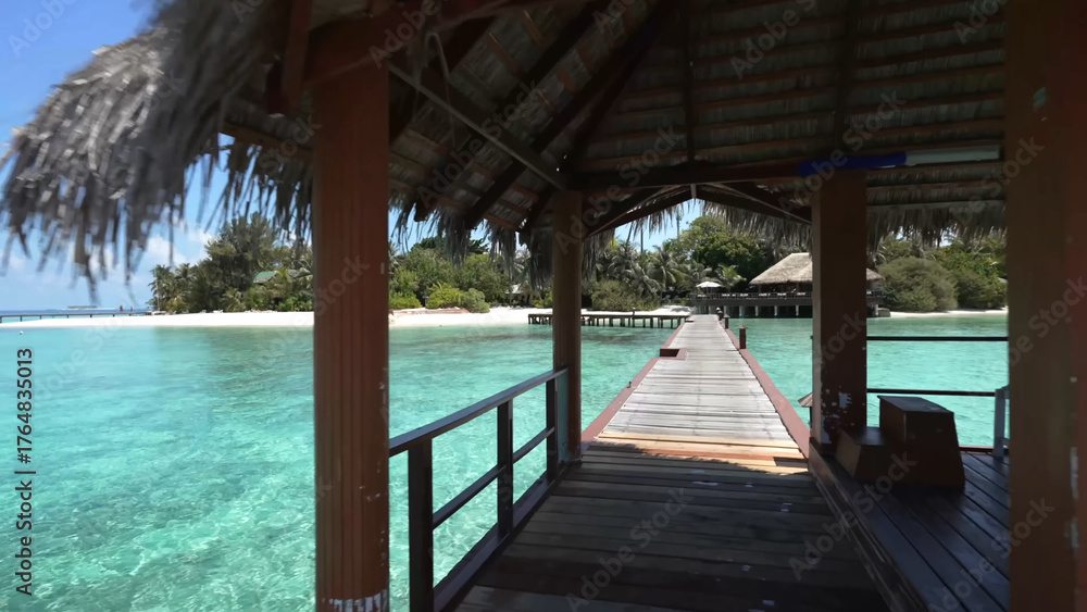 Obraz premium Luxury resort photo of Maldives tropical paradise island in Indian Ocean with palm trees, overwater thatched bungalows, wooden bridge. Beautiful photography, coral reef, azure ocean, sky with clouds. 
