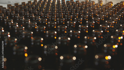 Fotografi Brown glass bottles arranged in perfectly aligned rows on a conveyor belt in a b