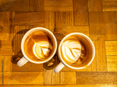 Hot latte, coffee with milk, and foam art on top in white ceramic cup on wooden table, in warm mood