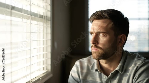 Thoughtful man looking out window in soft daylight