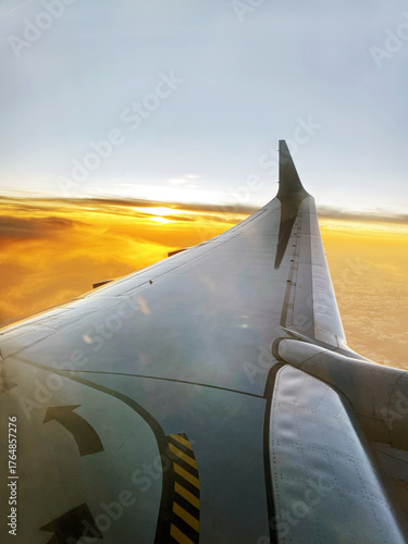 Photo showing the wing during the airplane flight.  
Jet plane on a vivid golden sunset with the wing lit by the twilight of sunset.  