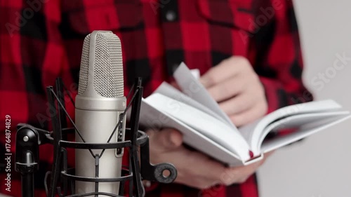 Close up of man flipping through a book near a microphone. Recording audiobook using microphone.