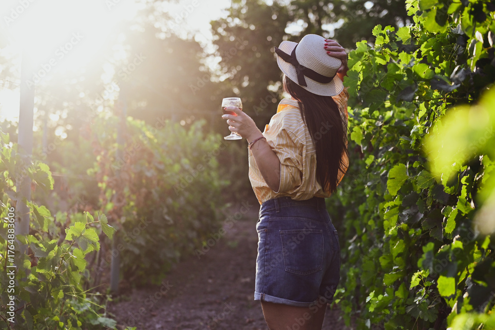 Fototapeta premium Happy beautiful Smiling woman walking at wineyard with a Glass of Red wine.Wine tourism at Tuscany,Italy