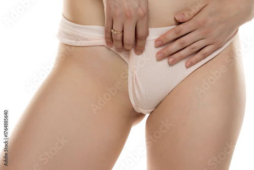 Studio shot of woman’s torso pulling aside underwear to expose bikini zone on white background.